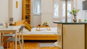 Een compacte, moderne kamer met een bed, een bureau en een kitchenette.