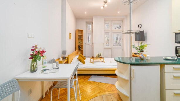 Een kleine hotelkamer met een bed, nachtkastje en een klein bureau. Er is een raam met uitzicht, een flatscreen televisie aan de muur en een magnetron in de kitchenette.