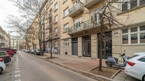 Una strada fiancheggiata da auto parcheggiate e alberi, con edifici dotati di balconi e una strada libera.