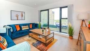Un salon moderne avec un canapé bleu, une table basse en bois et une grande porte-fenêtre coulissante donnant sur un espace extérieur.