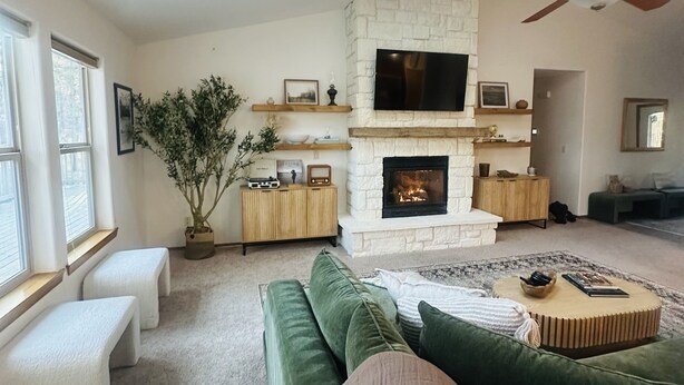 Una sala de estar con chimenea de piedra, un televisor de pantalla plana y un ventilador de techo.