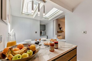 A modern kitchen with a marble countertop, a fruit bowl, a coffee maker, and a breakfast setting. - 3 Bed in St. Ives (oc-m27586) (St Ives)