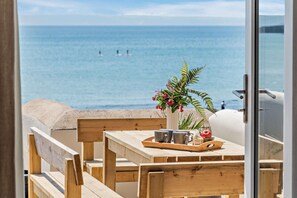A wooden table with a tray, a vase with flowers, and a view of the sea. - 2 Bed in Croyde (oc-r27591) (Croyde)