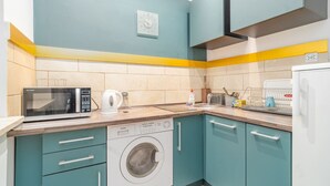 Uma cozinha compacta com armários verde-água, micro-ondas, lava-louças e pia.