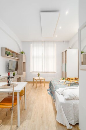 A modern bedroom with a bed, bedside table, and a desk with a chair. - Kraków Old Town Studio N1 – by Rentujemy (Kraków)