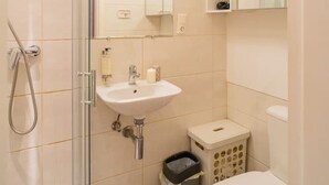Un baño con cabina de ducha de vidrio, lavabo, inodoro y espejo.