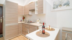 Una cocina moderna con armarios de madera, encimera blanca y un comedor con una mesa lista para dos.
