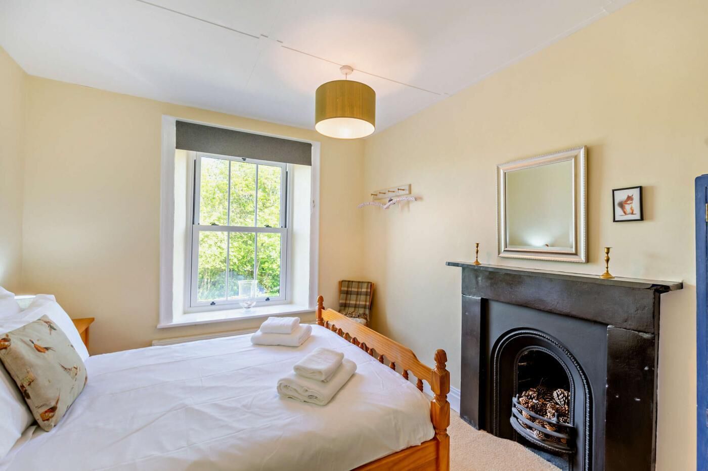 Un dormitorio con cama, chimenea, ventana y espejo.