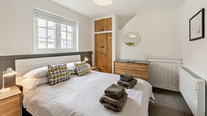 Une chambre à coucher comprenant un lit, une lampe de chevet, une armoire en bois, un radiateur et une fen être.