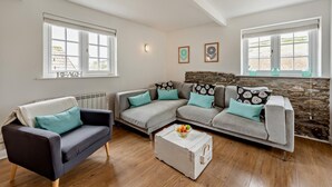 Un salon avec un canapé gris, un fauteuil noir et une boîte de rangement blanche.