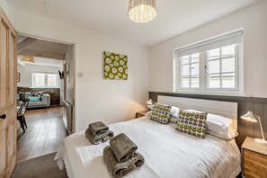Une chambre à coucher avec un lit, des oreillers, une lampe de chevet et une fenêtre.