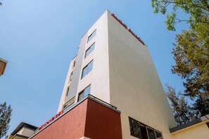 A tall building with a red and beige facade, multiple windows, and a clear sky in the background. - One-Bedroom Apartment #4 (Kigali)