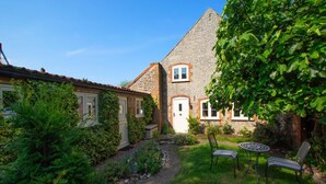 A traditional house with a brick exterior, a stone roof, and a small garden with a pathway and two chairs. - 2 Bed in Weybourne (oc-b16181) (Weybourne)
