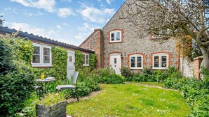 A brick house with a garden, a table with a chair, and a window. - 2 Bed in Weybourne (oc-b16181) (Weybourne)