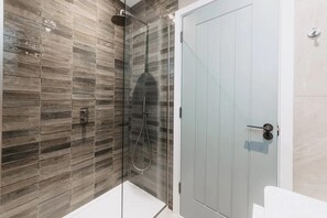 A modern bathroom with a glass-enclosed shower, a white door, and a tiled wall. - 3 Bed in Hayle (oc-t27597) (Hayle)