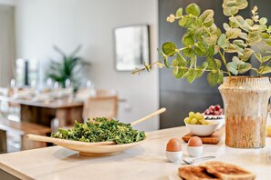 A dining table with a wooden bowl of greens, two eggs, a vase with green foliage, and a bowl of grapes. - 3 Bed in Hayle (oc-t27597) (Hayle)