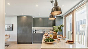 A modern kitchen with a central island, grey cabinetry, and pendant lighting. - 3 Bed in Hayle (oc-t27597) (Hayle)