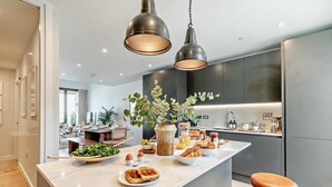 A modern kitchen with a marble island, pendant lighting, and a view into the dining area. - 3 Bed in Hayle (oc-t27597) (Hayle)