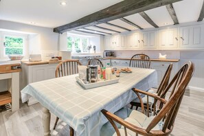 A dining area with a table set for breakfast, wooden chairs, and a kitchen in the background.