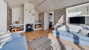 A modern living room with a stone wall, a fireplace, a sofa, and a television. - 3 Bed in St. Minver (oc-litmow) (Saint Minver)