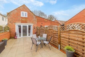 Une maison en briques avec un patio, une porte-fenêtre coulissante et une clôture en bois.