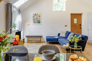 Ein modernes Wohnzimmer mit Sofa, Bank, Esstisch und einem Bild an der Wand.