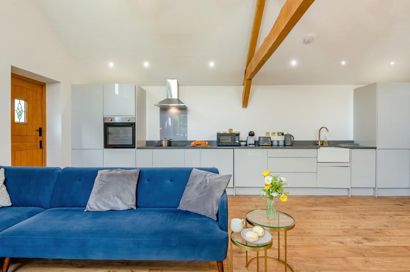 Una cocina moderna con armarios blancos, un sofá azul y un techo de madera.