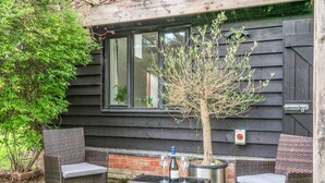 An outdoor seating area with wicker furniture, a small tree, and a window with a view of the interior. - 1 Bed in Dunston (oc-h27629) (Stoke Holy Cross)