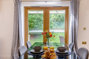 Ein Frühstückstisch mit Croissants, Orangensaft und einer Blumenvase.