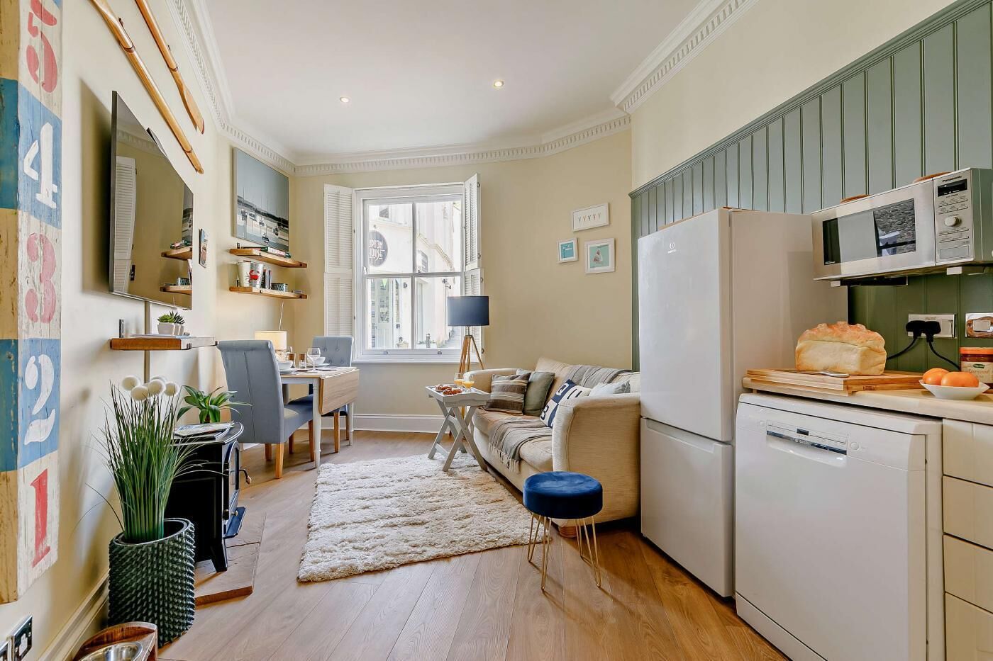 A compact kitchen with a dining area, a sofa, and a large window.