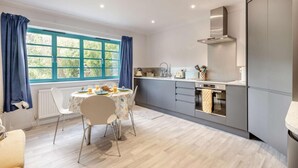 A modern kitchen with grey cabinets, a white countertop, and a window with blue curtains. - 2 Bed in St. Olaves (oc-t27605) (Haddiscoe)
