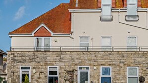 Ein zweistöckiges Gebäude mit einer Stein-Fassade, zahlreichen Fenstern und einem roten Ziegeldach.
