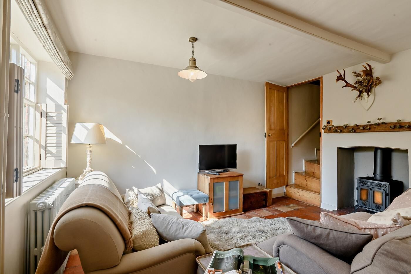 Una sala de estar acogedora con sofá, televisor, chimenea y una escalera.