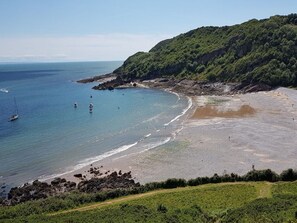 A coastal landscape with a beach, boats, and a forested hill. - 3 Bed in Mumbles (oc-t27675) (The Mumbles)