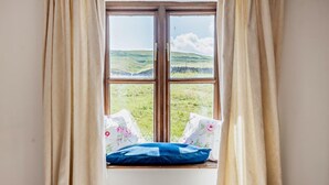 A room with a window overlooking a grassy landscape.