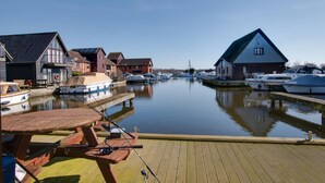 Een jachthaven met boten afgemeerd, houten steigers en gebouwen met schuine daken.