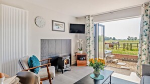 Un moderno salón con chimenea, televisor y vistas a un campo para caballos.