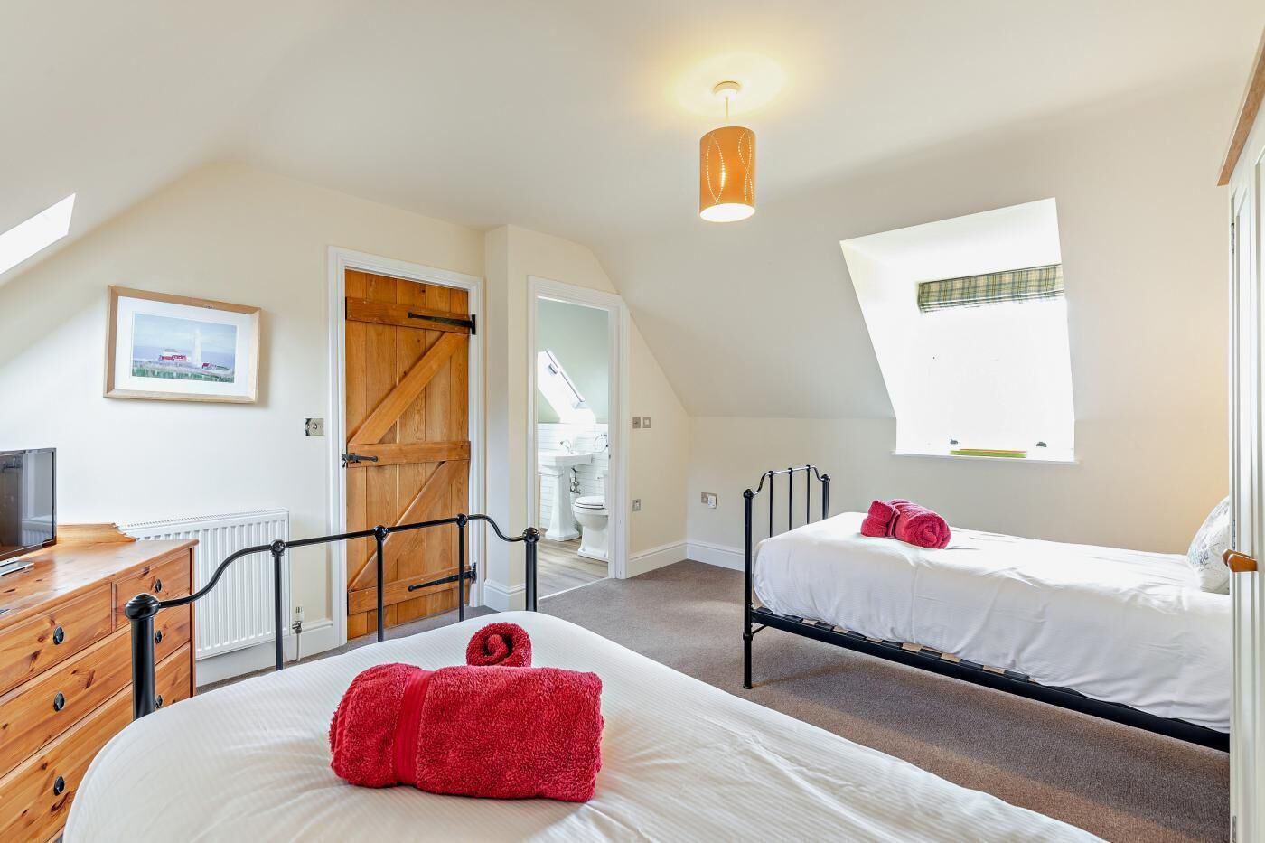 Ein Schlafzimmer mit zwei Betten, einem Holzkoffer, einem Heizkörper, einer Holztür und einem Fenster mit Blick.