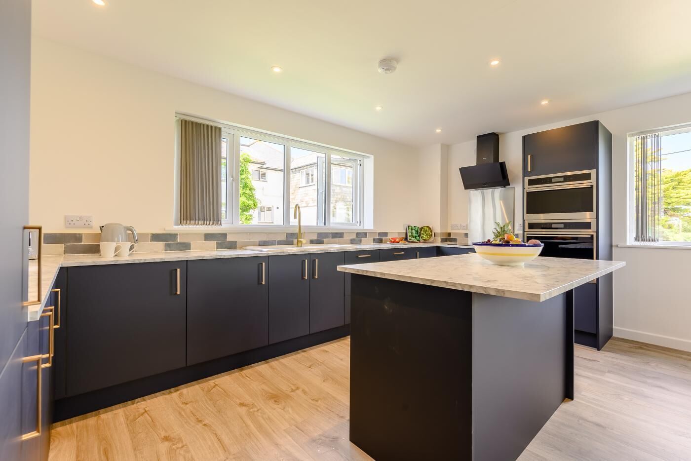 A modern kitchen with dark cabinetry, a marble countertop, and built-in appliances.