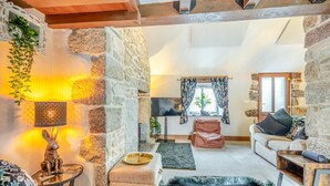 Una sala de estar acogedora con paredes de piedra, chimenea, televisor y asientos cómodos.
