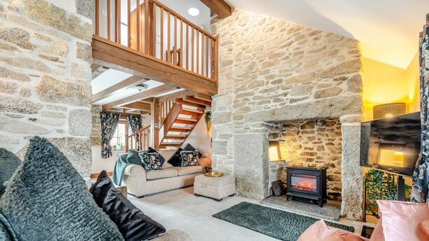 Una sala de estar acogedora con chimenea de piedra, un sofá y una televisión.