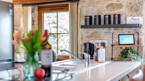 Una cocina moderna con pared de piedra, una cafetera y un reloj digital que marca 1:12.