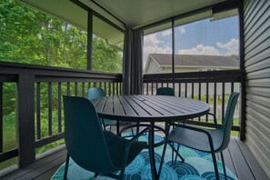Une terrasse extérieure couverte avec une table ronde et quatre chaises.