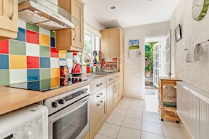 A modern kitchen with wooden cabinets, a colorful backsplash, and a view to the outside.