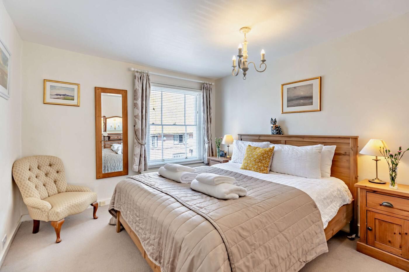 Een hotelkamer met een groot bed, een stoel, een nachtkastje en een kroonluchter.