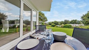 An outdoor dining area with a table set for two, a glass pitcher, and a bowl. - 2 Bed in Saundersfoot (oc-s27727) (Saundersfoot)