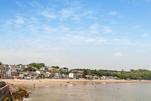 A coastal town with a sandy beach, houses, and a clear sky. - 2 Bed in Saundersfoot (oc-s27727) (Saundersfoot)
