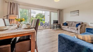 A modern living room with a dining area, a sofa, and a TV. - 2 Bed in Saundersfoot (oc-s27727) (Saundersfoot)
