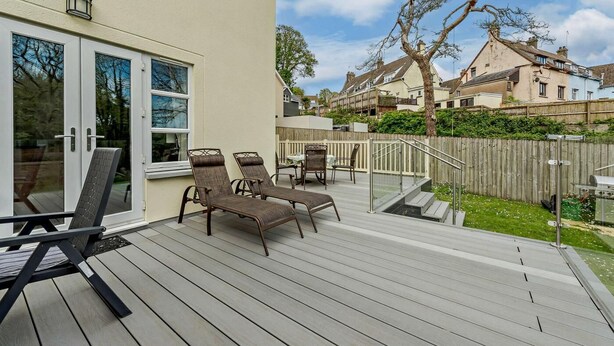 Una terrazza con mobili da esterno, una recinzione in legno e vista sulle case vicine.