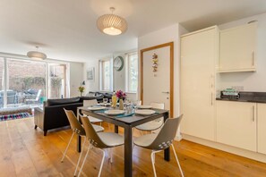 A modern kitchen with a dining area, wooden flooring, and a view to the outside. - 2 Bed in Southwold (oc-ftw2) (Southwold)